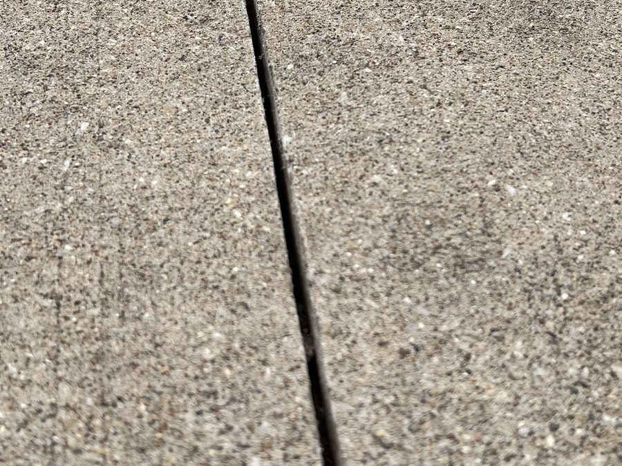 Wide-open unsealed driveway control joint letting water reach the base beneath the slab